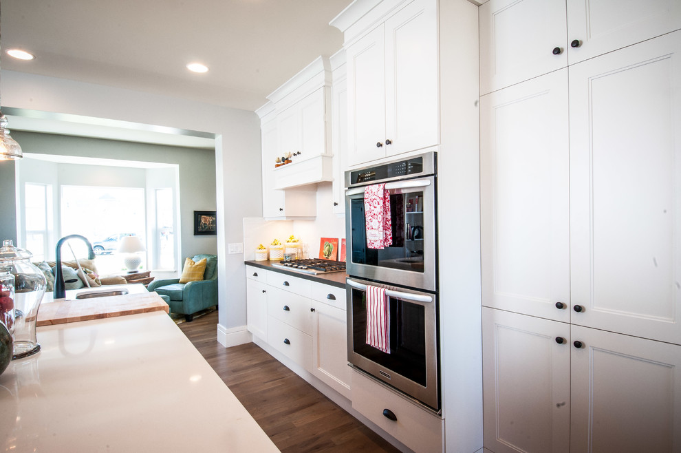 Example of a classic galley eat-in kitchen design in Salt Lake City with a farmhouse sink, shaker cabinets, white cabinets, quartzite countertops, white backsplash, subway tile backsplash and stainless steel appliances