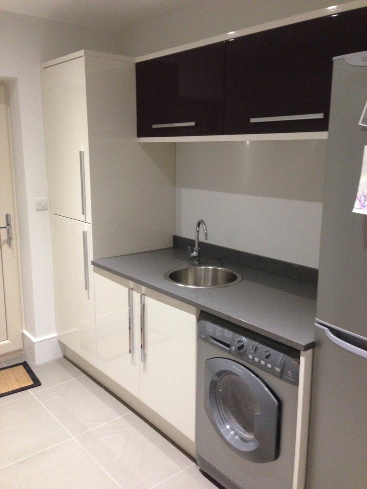 Photo of a small contemporary galley kitchen pantry in Cambridgeshire with a built-in sink, flat-panel cabinets, beige cabinets, quartz worktops, stainless steel appliances and ceramic flooring.