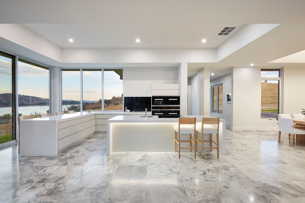 Large minimalist l-shaped limestone floor eat-in kitchen photo in Sydney with an undermount sink, gray cabinets, quartz countertops, white backsplash, glass sheet backsplash, stainless steel appliances and two islands
