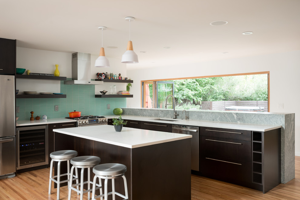 Contemporary l-shaped kitchen in Denver with a submerged sink, composite countertops, stainless steel appliances, light hardwood flooring, an island, flat-panel cabinets, dark wood cabinets, blue splashback and matchstick tiled splashback.