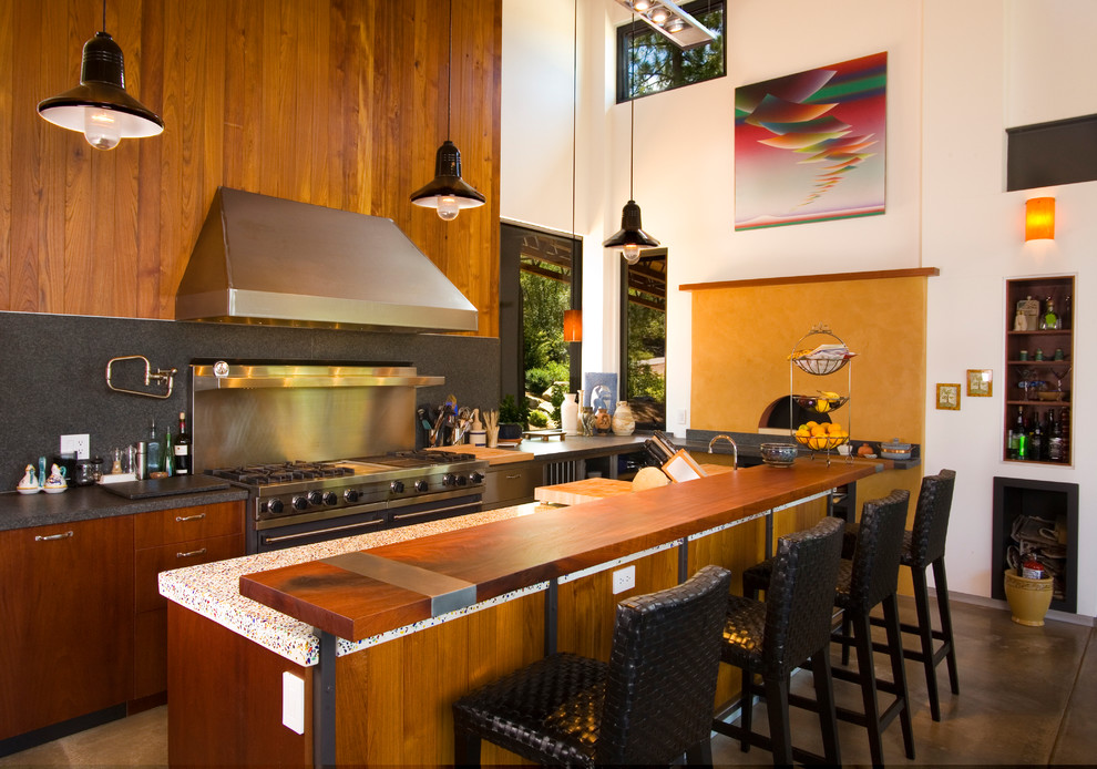Idées déco pour une cuisine contemporaine en bois brun avec un placard à porte plane, une crédence grise, un électroménager en acier inoxydable et sol en béton ciré.