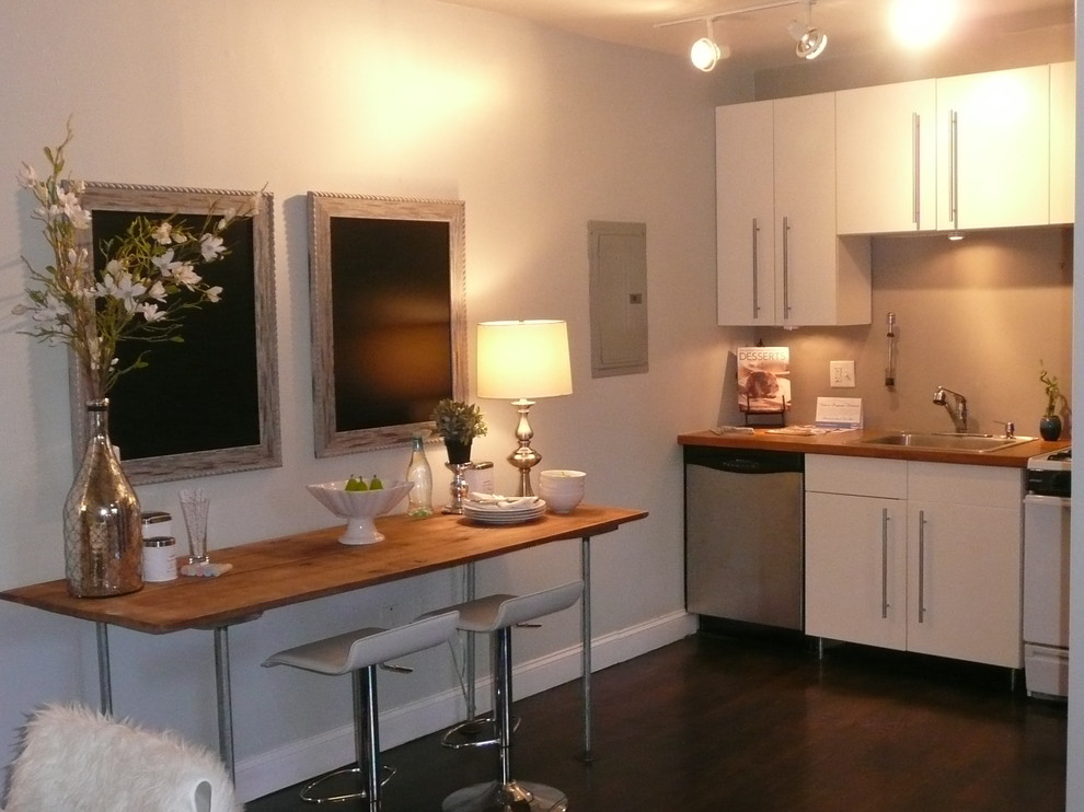 Photo of a small industrial single-wall kitchen/diner in Boston with a built-in sink, flat-panel cabinets, white cabinets, stainless steel appliances, dark hardwood flooring and no island.