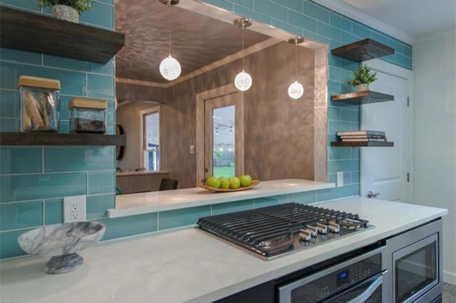 Cette photo montre une cuisine parallèle tendance avec un placard sans porte, un plan de travail en quartz modifié, une crédence bleue, une crédence en carreau de verre, un électroménager en acier inoxydable et aucun îlot.