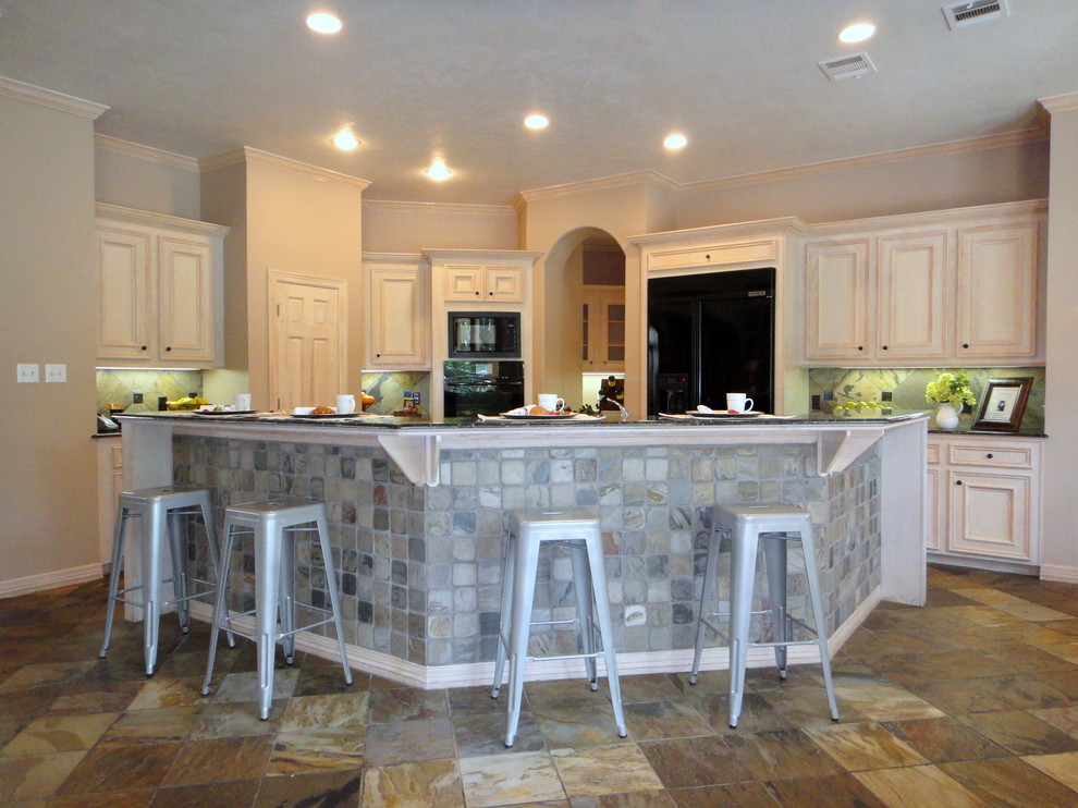 Example of a large mountain style l-shaped slate floor eat-in kitchen design in Houston with an undermount sink, raised-panel cabinets, light wood cabinets, granite countertops, gray backsplash, stone tile backsplash, black appliances and an island