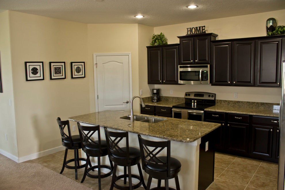Exemple d'une grande cuisine ouverte parallèle tendance avec un évier 2 bacs, des portes de placard noires, un plan de travail en granite, une crédence beige et un sol en carrelage de céramique.