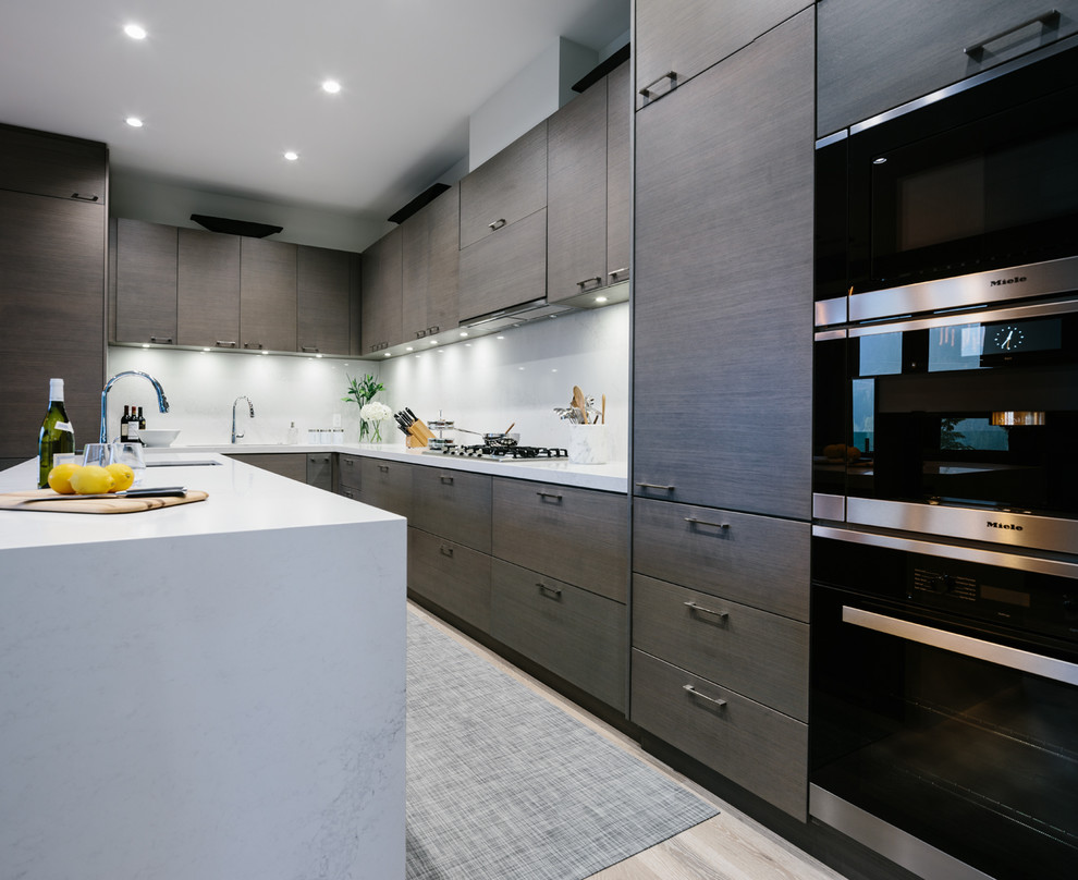 Photo of a large contemporary l-shaped kitchen/diner in Vancouver with a submerged sink, flat-panel cabinets, dark wood cabinets, quartz worktops, white splashback, stone slab splashback, integrated appliances, medium hardwood flooring, an island and grey floors.