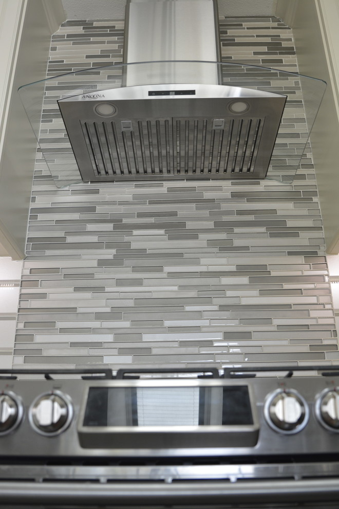 Exempel på ett stort modernt flerfärgad flerfärgat l-kök, med en dubbel diskho, luckor med profilerade fronter, beige skåp, granitbänkskiva, vitt stänkskydd, stänkskydd i glaskakel, rostfria vitvaror, laminatgolv, en köksö och flerfärgat golv