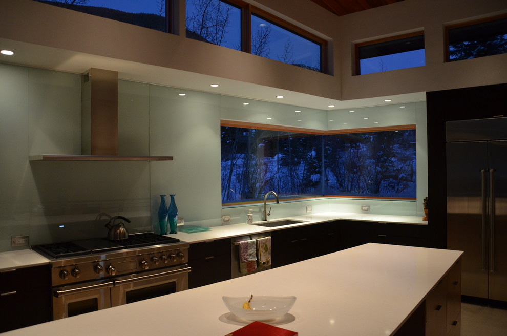 Ispirazione per una cucina design di medie dimensioni con lavello sottopiano, ante lisce, ante nere, paraspruzzi blu, paraspruzzi con lastra di vetro, elettrodomestici in acciaio inossidabile e pavimento in cemento