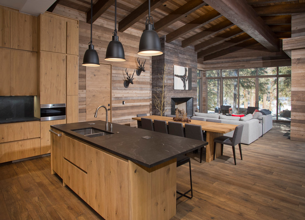 Photo of a rustic l-shaped open plan kitchen in Denver with flat-panel cabinets, light wood cabinets, black splashback and an island.