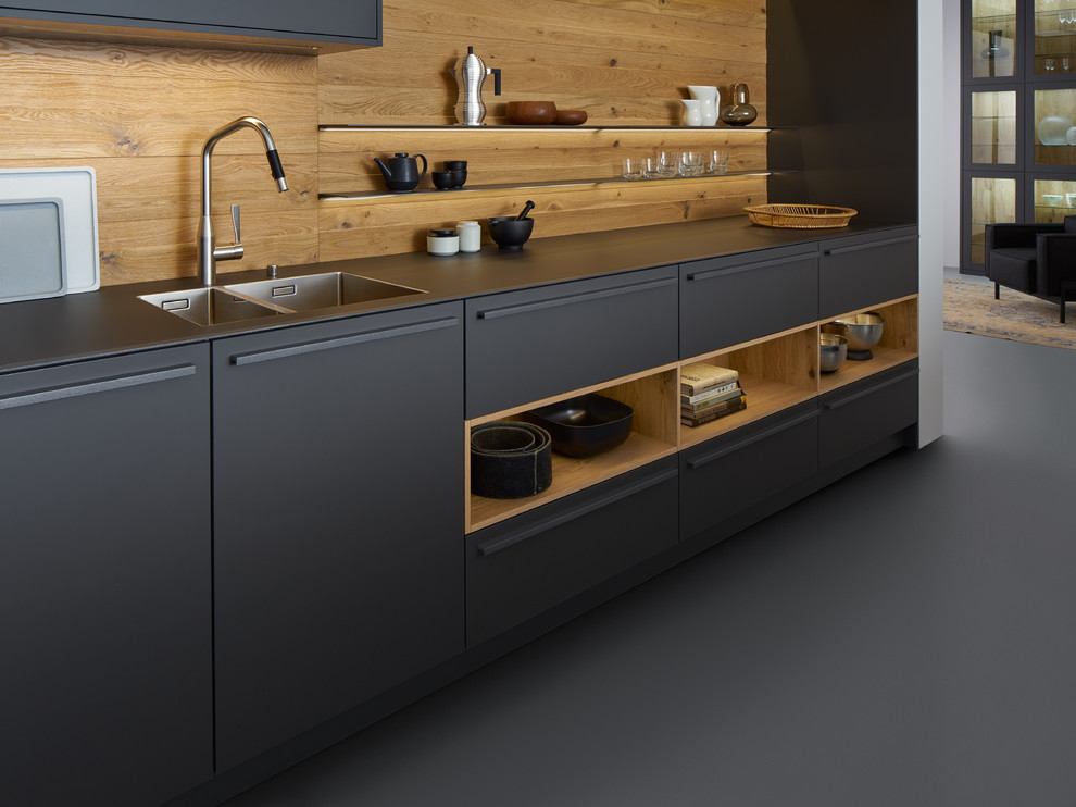 Esempio di una grande cucina minimalista con lavello integrato, ante lisce, ante nere, paraspruzzi in legno, elettrodomestici neri e pavimento in cemento