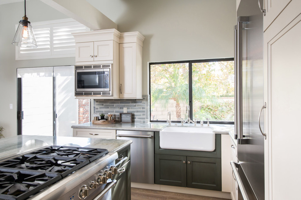 Lantlig inredning av ett mellanstort kök, med luckor med infälld panel, vita skåp, rostfria vitvaror, ljust trägolv och en köksö