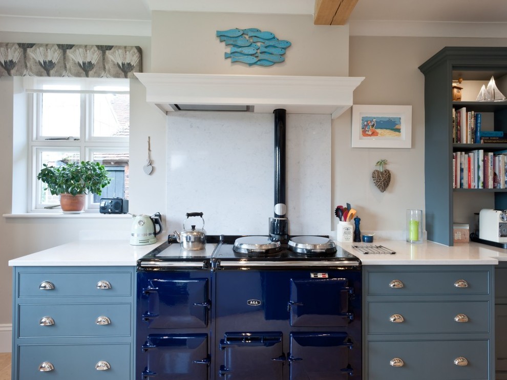 Cette photo montre une grande cuisine ouverte nature en U avec un évier posé, un placard à porte shaker, des portes de placard bleues, un plan de travail en surface solide, un électroménager de couleur et îlot.