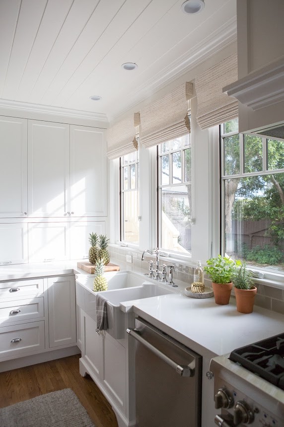 Eat-in kitchen - mid-sized coastal l-shaped medium tone wood floor and brown floor eat-in kitchen idea in Santa Barbara with a farmhouse sink, shaker cabinets, white cabinets, wood countertops, gray backsplash, subway tile backsplash, stainless steel appliances and an island