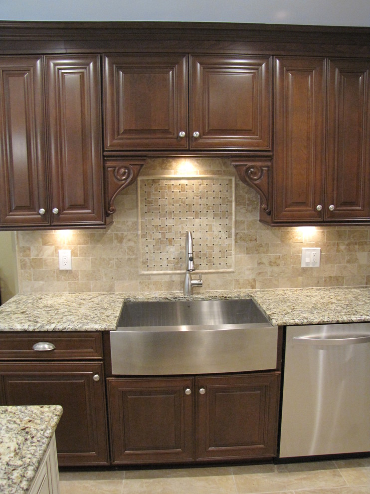 Example of a mid-sized classic l-shaped porcelain tile eat-in kitchen design in New York with a farmhouse sink, raised-panel cabinets, dark wood cabinets, granite countertops, beige backsplash, stone tile backsplash, stainless steel appliances and an island