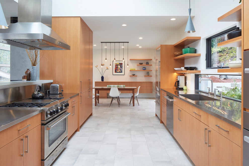 Idéer för att renovera ett stort funkis grå grått kök, med en undermonterad diskho, släta luckor, skåp i mellenmörkt trä, bänkskiva i rostfritt stål, rostfria vitvaror, klinkergolv i porslin, en köksö och grått golv