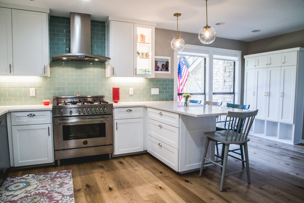 Example of a large transitional l-shaped medium tone wood floor eat-in kitchen design in Austin with a farmhouse sink, shaker cabinets, white cabinets, quartzite countertops, blue backsplash, subway tile backsplash, stainless steel appliances and a peninsula