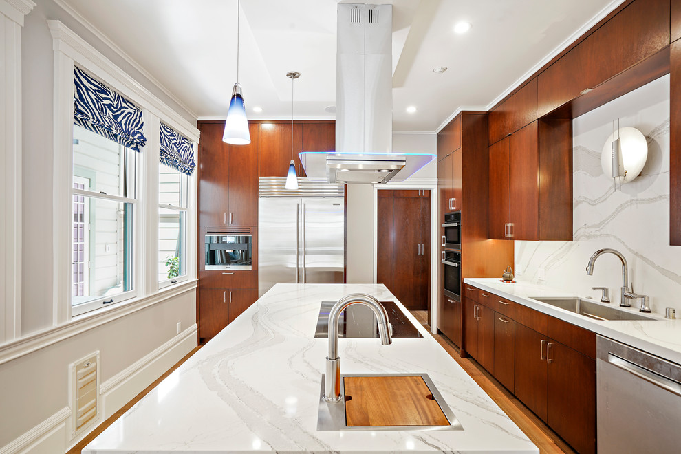 Inspiration for a medium sized classic galley kitchen pantry in San Francisco with a submerged sink, flat-panel cabinets, medium wood cabinets, engineered stone countertops, white splashback, stone slab splashback, stainless steel appliances, light hardwood flooring, an island, brown floors and white worktops.