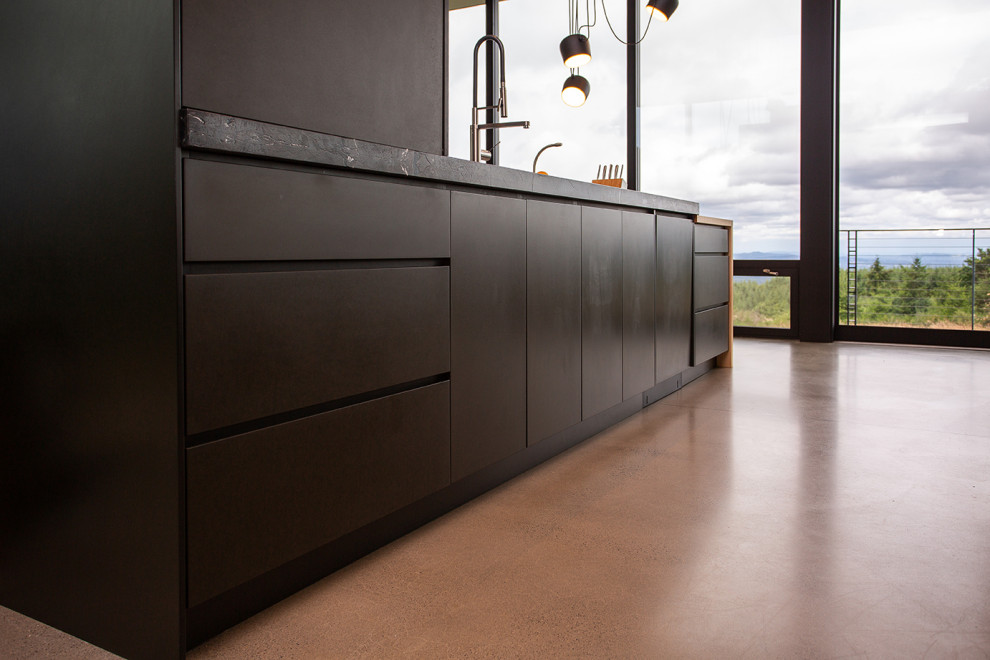 Inspiration for a modern l-shaped kitchen/diner in Portland with flat-panel cabinets, black cabinets, wood worktops, an island, a built-in sink, concrete flooring, beige floors and black worktops.