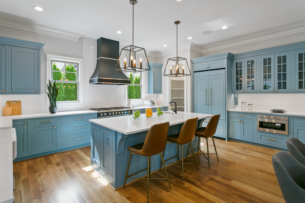 Inspiration for a medium sized classic u-shaped kitchen in Other with shaker cabinets, blue cabinets, white splashback, medium hardwood flooring, an island, brown floors, white worktops, a belfast sink and black appliances.