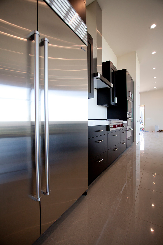 Esempio di una cucina minimalista di medie dimensioni con lavello a vasca singola, ante lisce, ante nere, paraspruzzi bianco e elettrodomestici in acciaio inossidabile