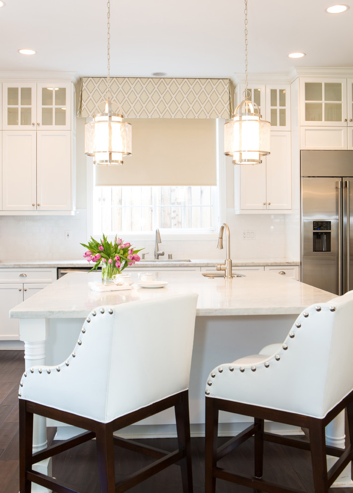 Example of a mid-sized classic single-wall dark wood floor enclosed kitchen design in Los Angeles with an undermount sink, shaker cabinets, white cabinets, marble countertops, white backsplash, ceramic backsplash, stainless steel appliances and an island