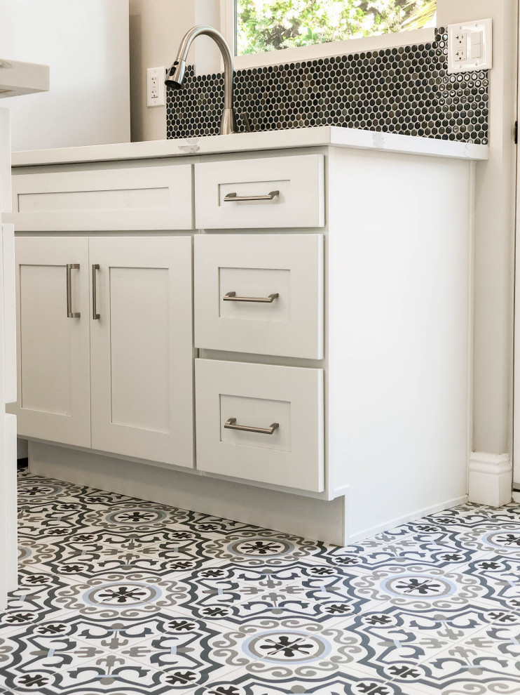 Idéer för mellanstora funkis vitt kök, med en nedsänkt diskho, luckor med infälld panel, vita skåp, blått stänkskydd, vita vitvaror, en köksö, vitt golv, bänkskiva i kvarts, stänkskydd i cementkakel och klinkergolv i keramik