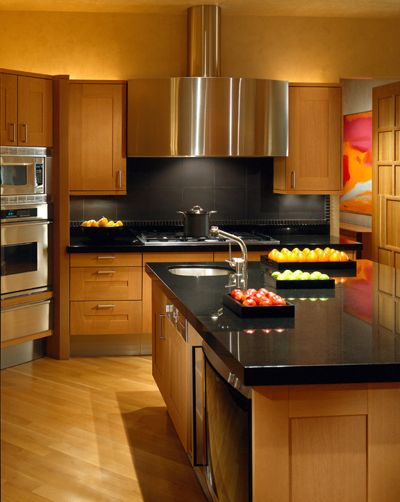 Example of a large trendy u-shaped light wood floor enclosed kitchen design in Miami with a drop-in sink, raised-panel cabinets, light wood cabinets, marble countertops, black backsplash, cement tile backsplash, stainless steel appliances and an island