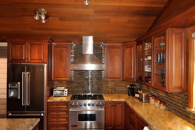 Cette photo montre une cuisine américaine montagne en U et bois brun de taille moyenne avec un placard à porte vitrée, une crédence en céramique, un électroménager en acier inoxydable et îlot.