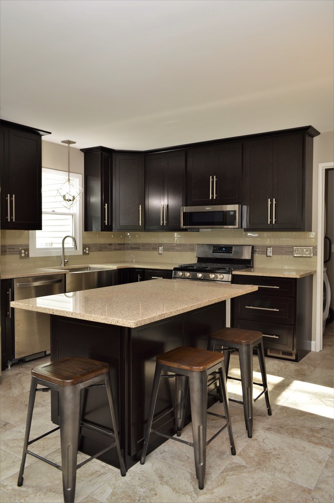 Mid-sized transitional l-shaped ceramic tile and beige floor eat-in kitchen photo in Chicago with a farmhouse sink, shaker cabinets, black cabinets, quartzite countertops, beige backsplash, stainless steel appliances, an island and beige countertops