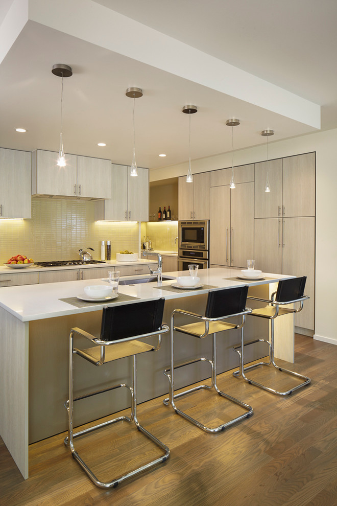 Moderne Küche mit Unterbauwaschbecken, flächenbündigen Schrankfronten, weißen Schränken, Küchenrückwand in Gelb und Küchengeräten aus Edelstahl in Denver