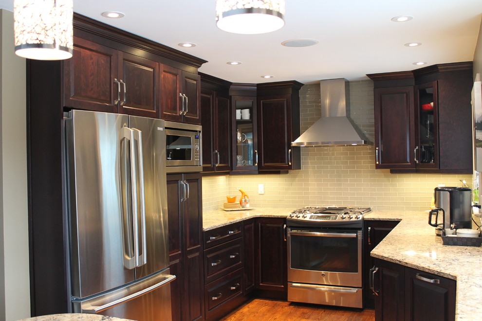 Small trendy u-shaped medium tone wood floor eat-in kitchen photo in Ottawa with a double-bowl sink, raised-panel cabinets, dark wood cabinets, quartz countertops, beige backsplash, glass tile backsplash, stainless steel appliances and a peninsula