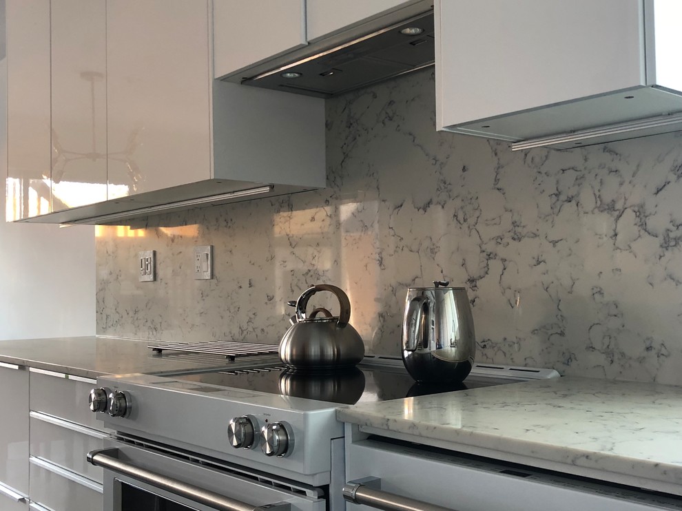 Inspiration for a medium sized contemporary single-wall kitchen in Vancouver with a double-bowl sink, flat-panel cabinets, white cabinets, quartz worktops, white splashback, stone slab splashback, white appliances, concrete flooring, grey floors and white worktops.