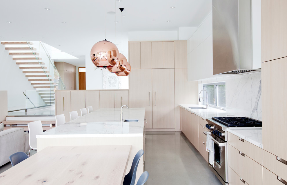 Idee per una grande cucina design con lavello sottopiano, ante lisce, ante in legno chiaro, paraspruzzi bianco, elettrodomestici da incasso e pavimento in cemento