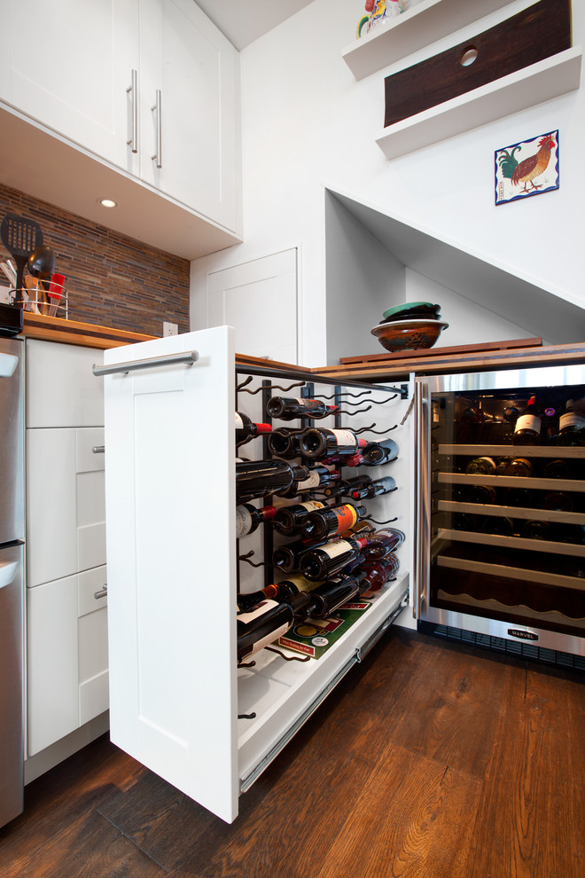 Inspiration for a transitional enclosed kitchen remodel in Vancouver with a farmhouse sink, shaker cabinets, white cabinets, wood countertops, brown backsplash, matchstick tile backsplash and stainless steel appliances