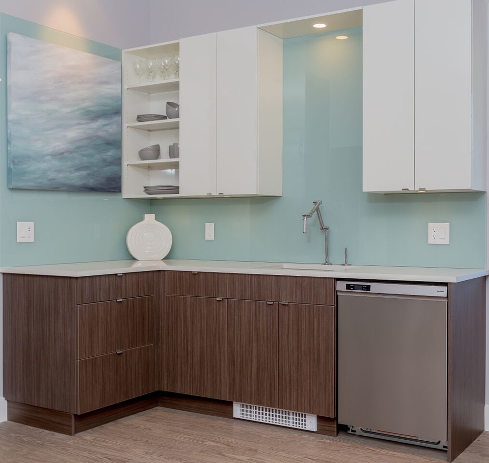 Example of a small trendy l-shaped light wood floor open concept kitchen design in Vancouver with an undermount sink, white cabinets, stainless steel appliances, no island, flat-panel cabinets, solid surface countertops, blue backsplash and glass sheet backsplash