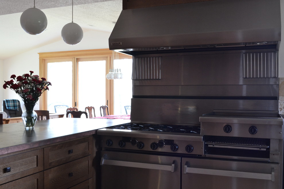 ポートランドにある中くらいなトラディショナルスタイルのおしゃれなキッチン (一体型シンク、シェーカースタイル扉のキャビネット、茶色いキャビネット、銅製カウンター、シルバーの調理設備、淡色無垢フローリング) の写真