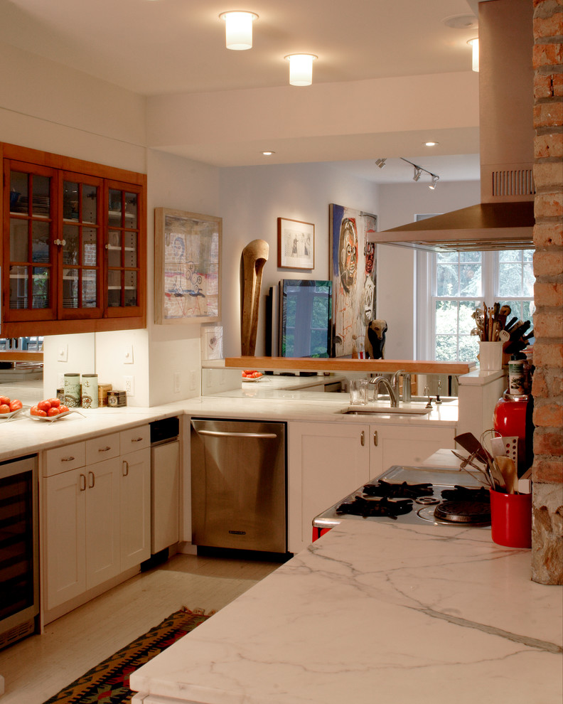 Example of a transitional u-shaped open concept kitchen design in New York with an undermount sink, white cabinets, stainless steel appliances, glass-front cabinets and marble countertops