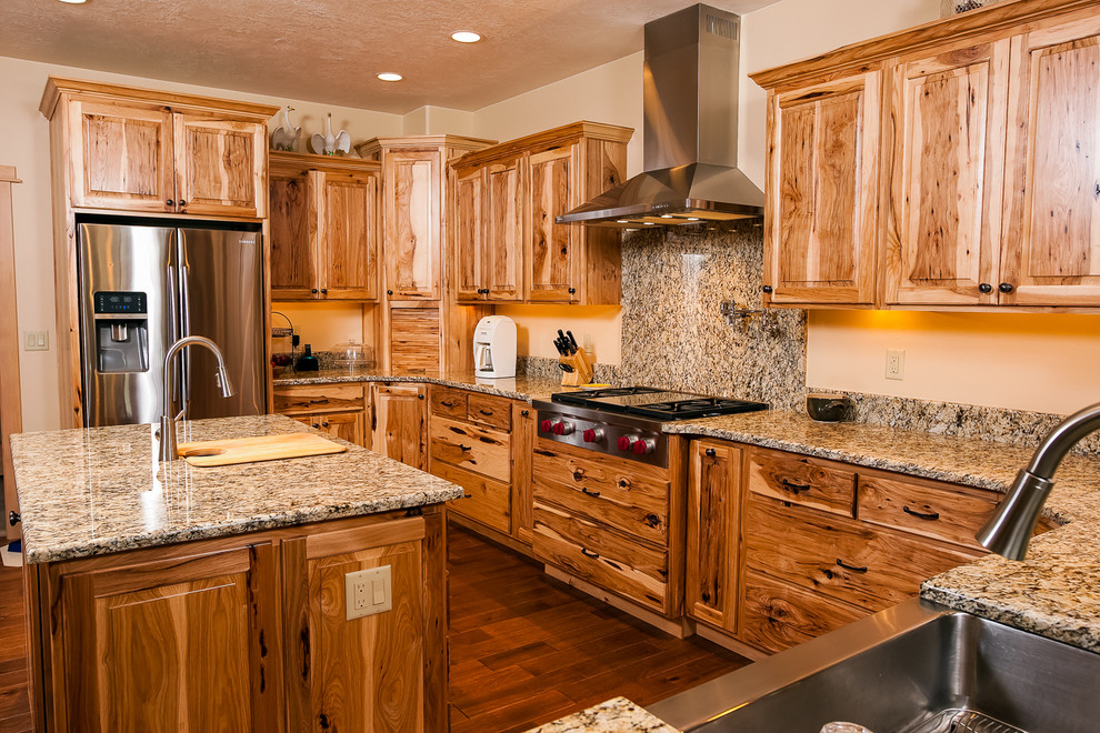 Foto på ett stort amerikanskt kök, med en rustik diskho, skåp i ljust trä, granitbänkskiva, beige stänkskydd, rostfria vitvaror, mörkt trägolv och en köksö