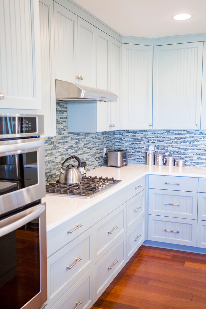 Foto di una cucina costiera di medie dimensioni con lavello sottopiano, ante a persiana, ante blu, paraspruzzi blu, paraspruzzi con piastrelle di vetro, elettrodomestici in acciaio inossidabile e pavimento in legno massello medio