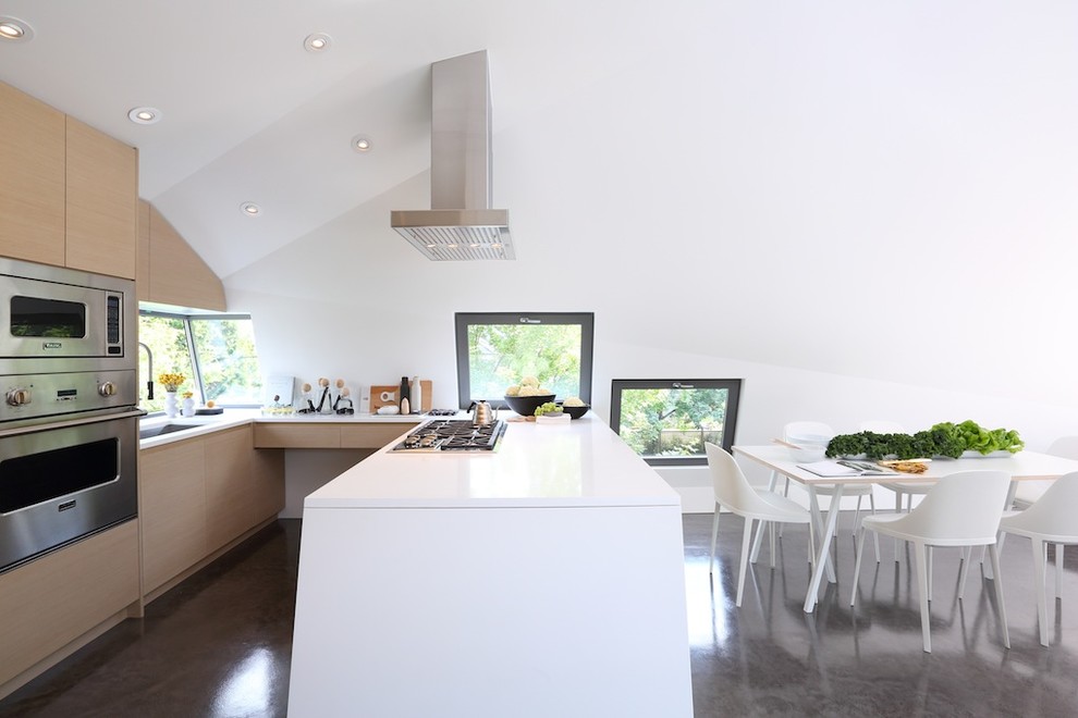 Bild på ett mellanstort funkis kök och matrum, med skåp i ljust trä, rostfria vitvaror, betonggolv, en köksö och en nedsänkt diskho