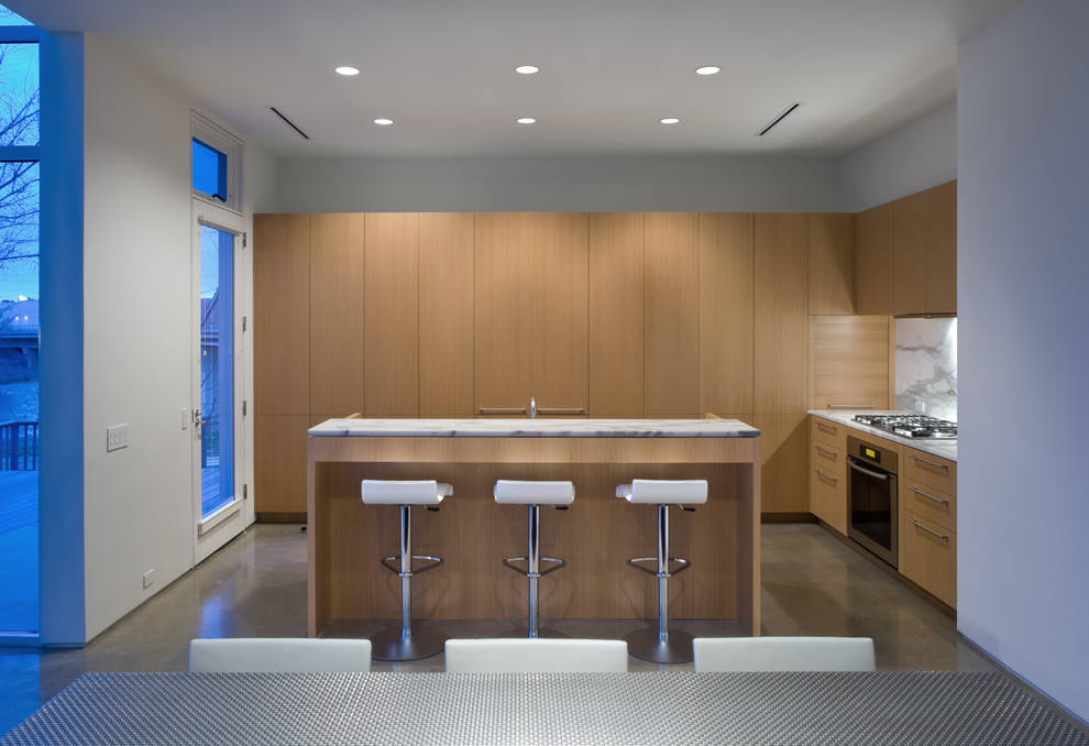 Moderne Wohnküche in L-Form mit flächenbündigen Schrankfronten, hellbraunen Holzschränken, Küchenrückwand in Weiß, Rückwand aus Stein, Elektrogeräten mit Frontblende und Kücheninsel in Dallas