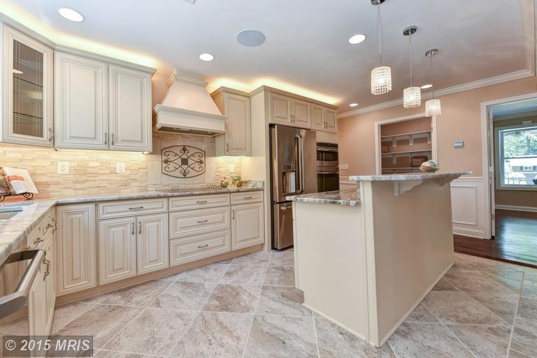 Inspiration for a large traditional l-shaped kitchen in DC Metro with a submerged sink, raised-panel cabinets, white cabinets, granite worktops, beige splashback, ceramic splashback, stainless steel appliances, ceramic flooring and an island.