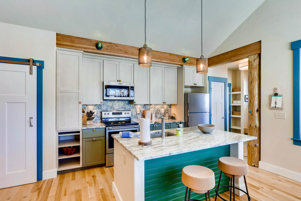 Bild på ett litet eklektiskt kök med öppen planlösning, med en undermonterad diskho, skåp i shakerstil, vita skåp, granitbänkskiva, blått stänkskydd, stänkskydd i glaskakel, rostfria vitvaror, ljust trägolv och en köksö