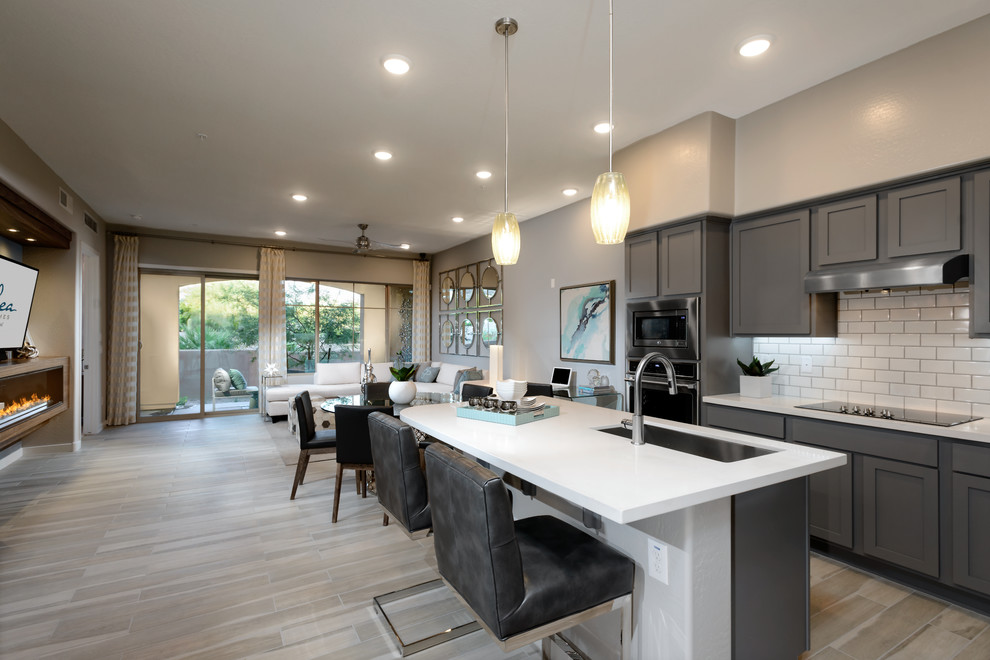 Design ideas for a medium sized contemporary l-shaped open plan kitchen in Phoenix with a submerged sink, raised-panel cabinets, grey cabinets, engineered stone countertops, white splashback, metro tiled splashback, stainless steel appliances, ceramic flooring and an island.