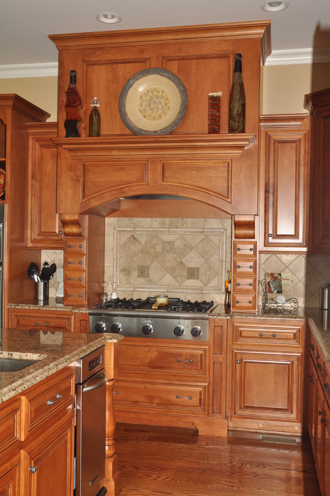 Bild på ett stort vintage kök, med en undermonterad diskho, luckor med upphöjd panel, skåp i mellenmörkt trä, granitbänkskiva, beige stänkskydd, stänkskydd i stenkakel, rostfria vitvaror, mellanmörkt trägolv och en köksö