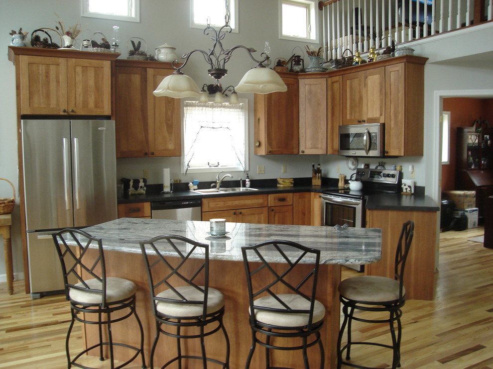 Exemple d'une grande cuisine chic en L et bois brun avec un évier posé, un placard à porte shaker, un électroménager en acier inoxydable, parquet clair et îlot.