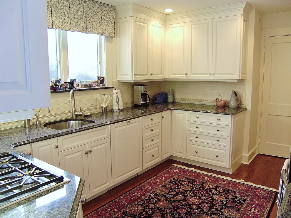Mittelgroße Klassische Küche in U-Form mit Unterbauwaschbecken, profilierten Schrankfronten, weißen Schränken, Granit-Arbeitsplatte, Küchenrückwand in Weiß, Küchengeräten aus Edelstahl und dunklem Holzboden in Boston