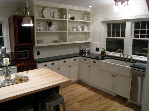 Photo of a medium sized traditional u-shaped kitchen/diner in Seattle with a belfast sink, beaded cabinets, white cabinets, soapstone worktops, white splashback, porcelain splashback, stainless steel appliances, medium hardwood flooring and an island.