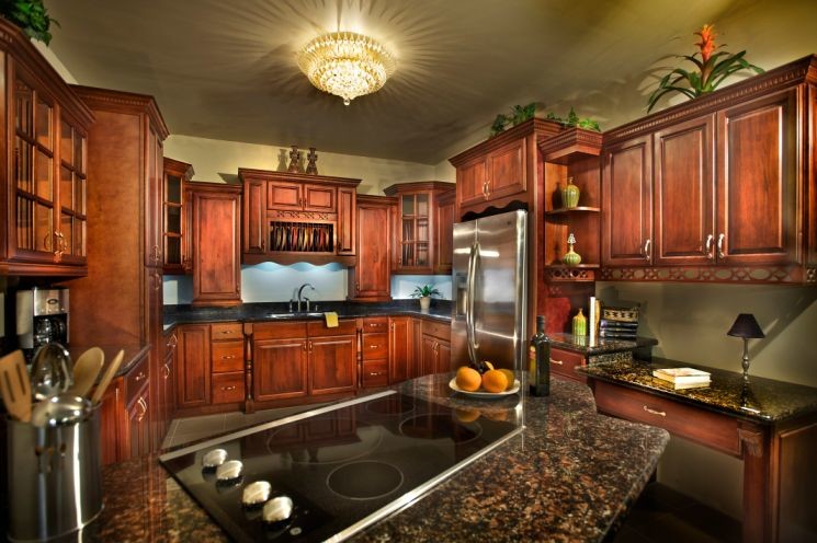 Exempel på ett mellanstort medelhavsstil kök, med en undermonterad diskho, luckor med upphöjd panel, skåp i mörkt trä, granitbänkskiva, svart stänkskydd, stänkskydd i keramik, rostfria vitvaror, ljust trägolv och en halv köksö