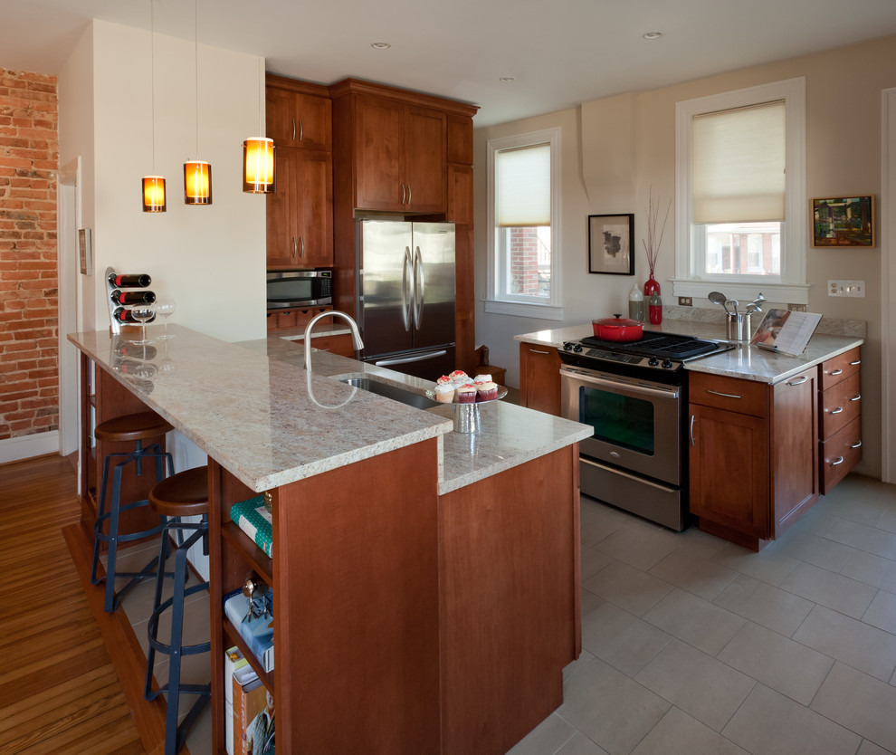 Mid-sized transitional l-shaped ceramic tile and beige floor open concept kitchen photo in DC Metro with shaker cabinets, medium tone wood cabinets, stainless steel appliances, an undermount sink, granite countertops, beige backsplash, stone slab backsplash and a peninsula